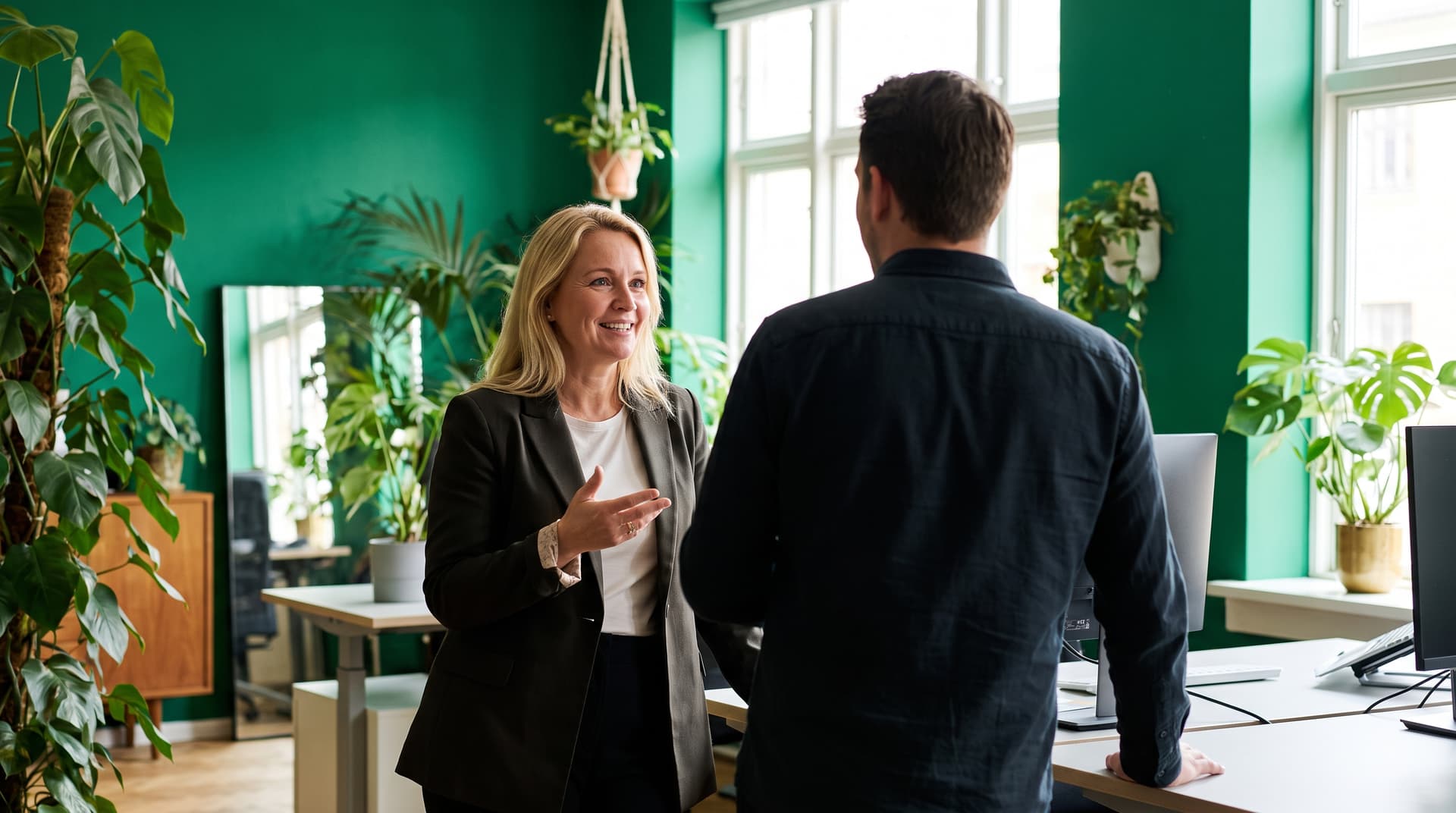 Two colleagues talking in a plant-filled office